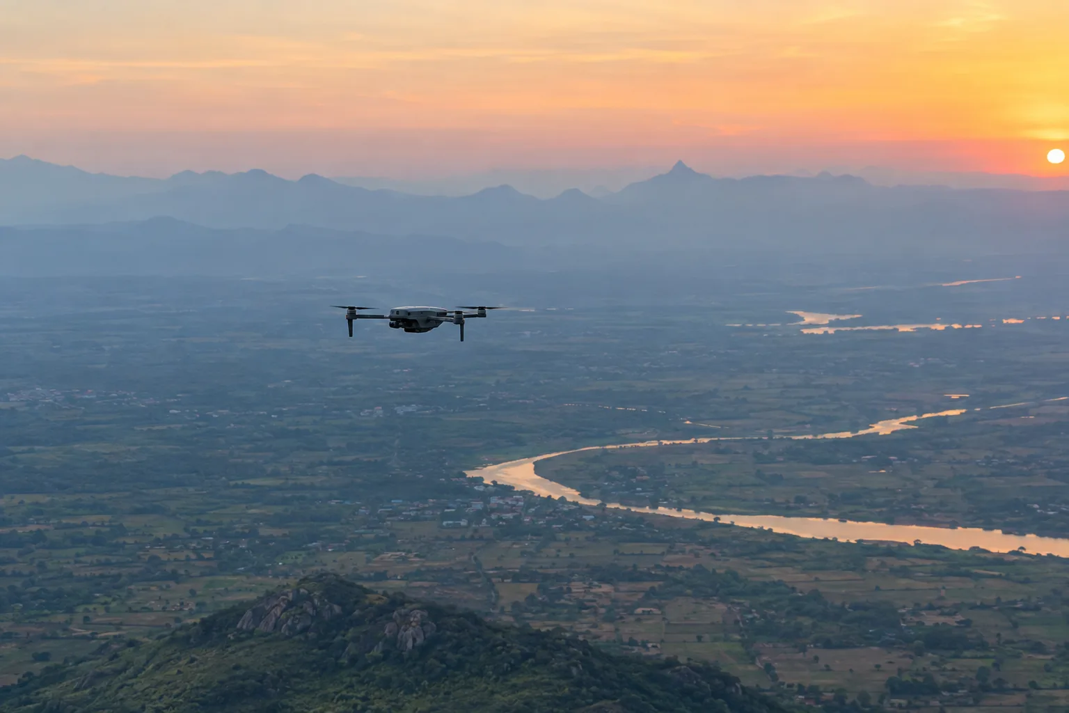 An aircraft at altitude over Indian terrain at first light, wide and calm, no text or overlays